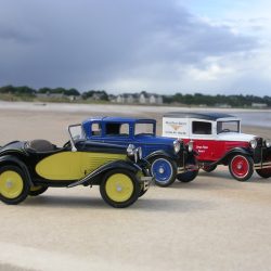 Green, blue and red American Austin models on a beach